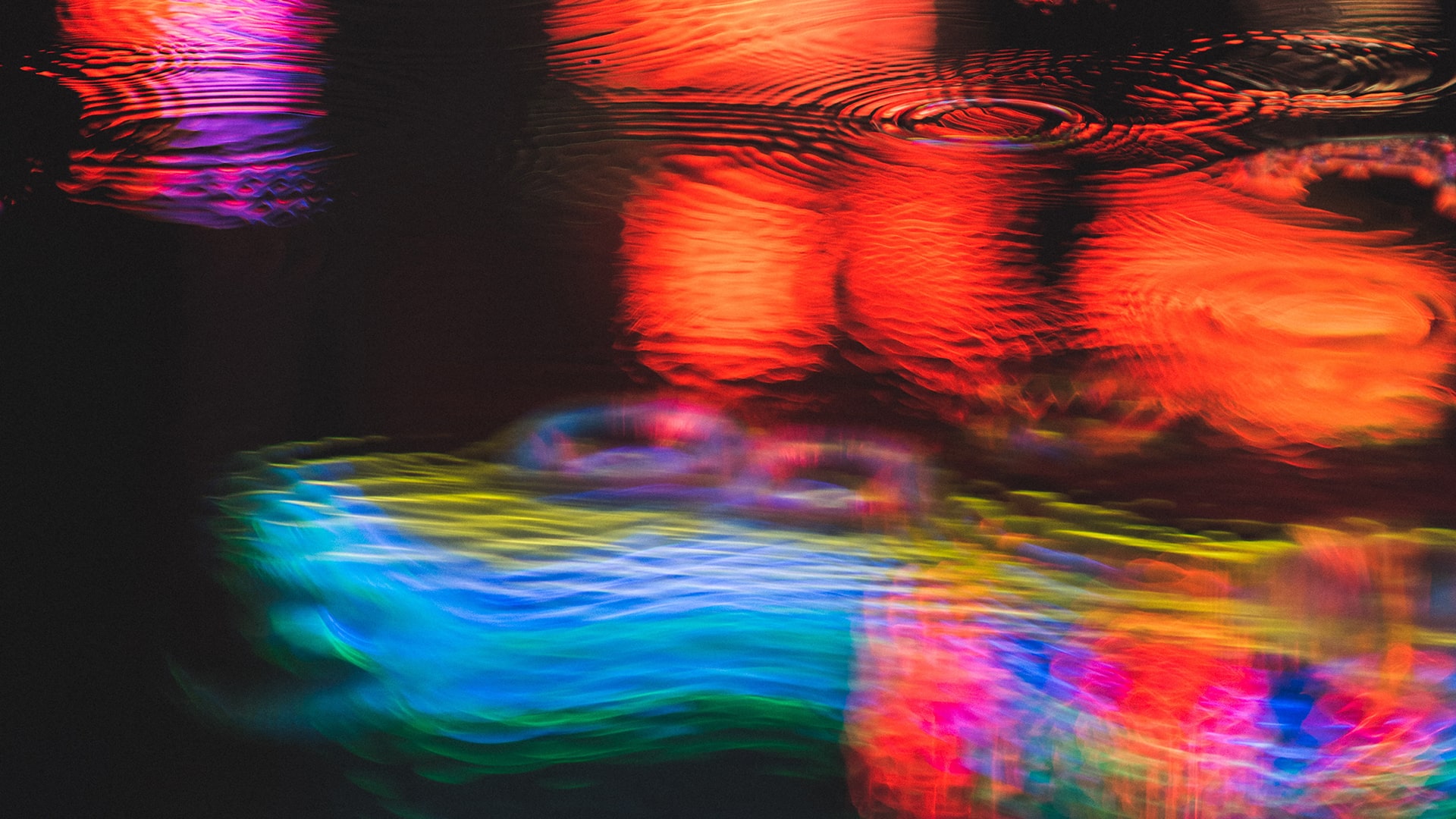 Disturbed water with blue, red and yellow colours shining on it.