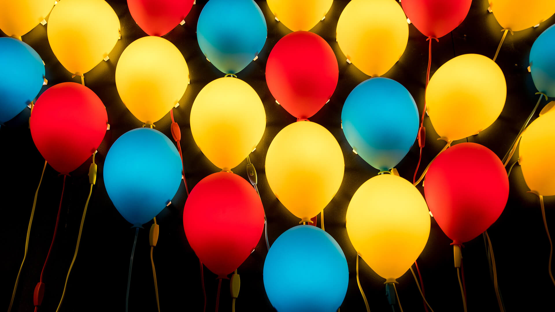 Red, blue and yellow balloons on a black background.