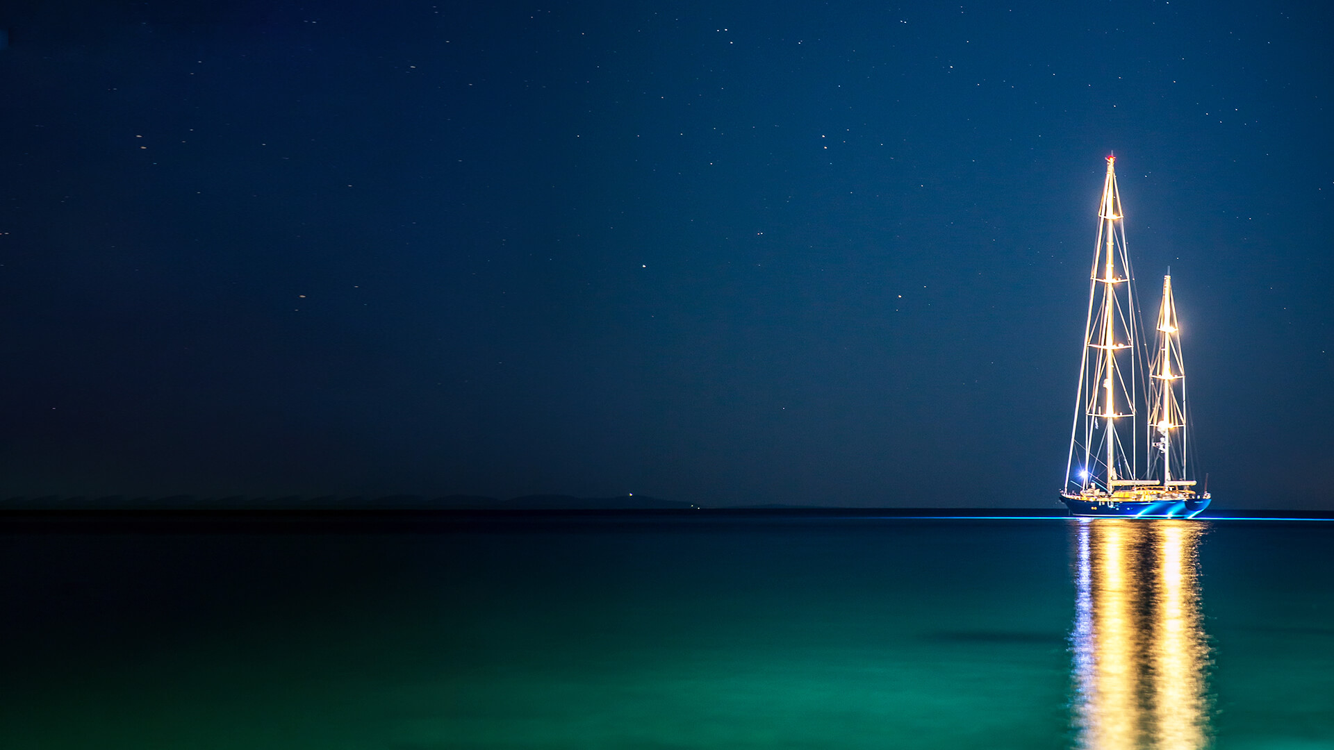 A two-sail ship in the middle of the sea at night.