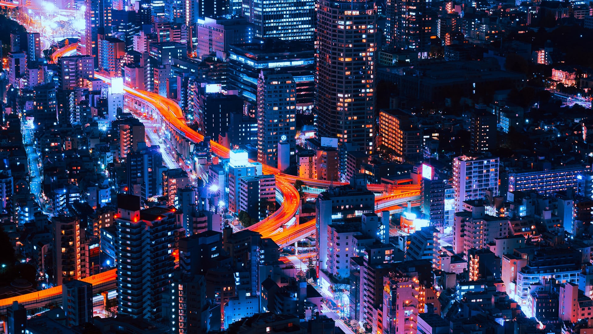 Metropolitan city at night with light on and a road, shining in red and yellow lights.