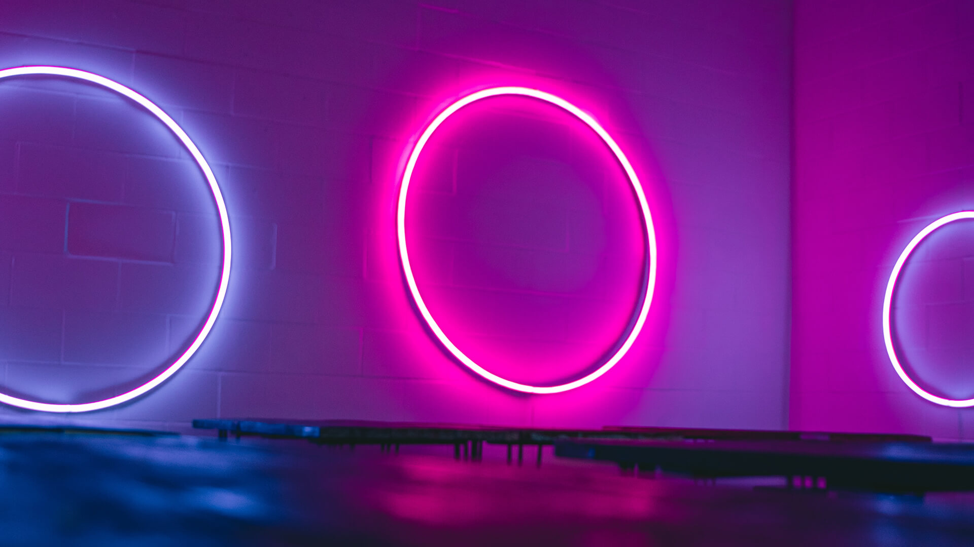 Purple neon circle signs on a purple brick wall.